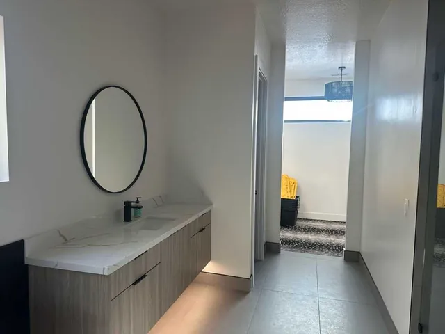 Bathroom vanity with round mirror and freshly painted white walls