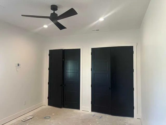 Bedroom with crisp white walls and black-painted closet doors