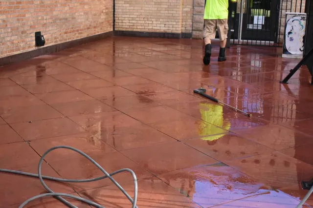 Wide commercial stone patio mid-wash with hoses