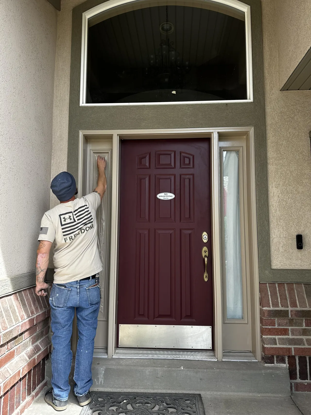 Painter detailing the trim around a maroon front door