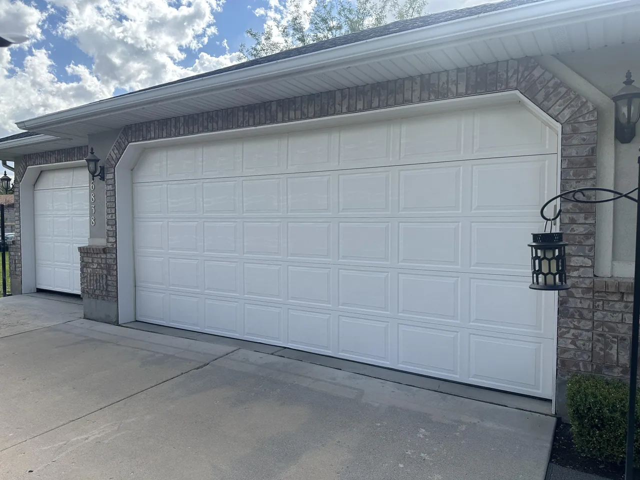White garage doors framed by stone columns on a home exterior