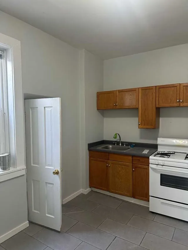 Kitchen repainted in light gray with wood cabinets and white appliances
