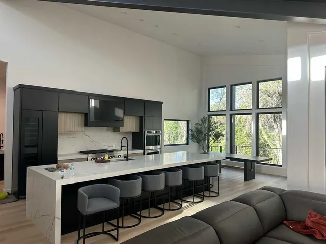 Modern kitchen with black cabinets, white island, and freshly painted walls