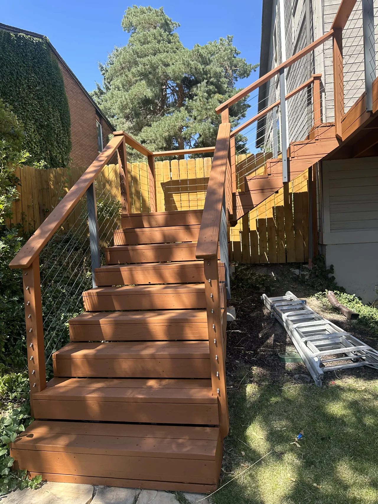 Deck staircase and railing freshly stained, with matching stained fence behind
