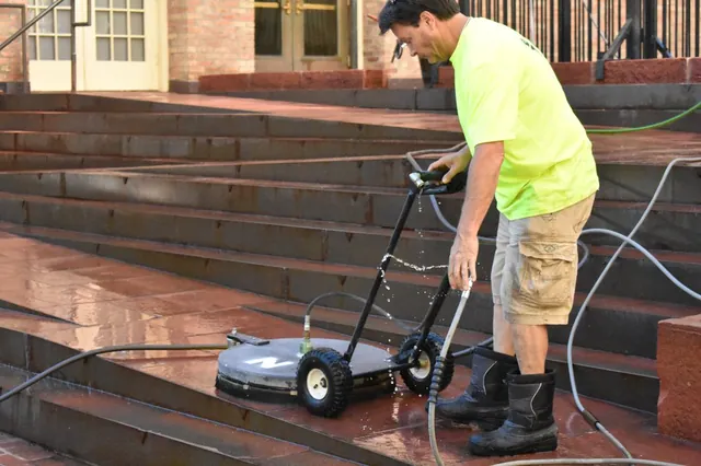 Technician guiding a surface cleaner down stone steps
