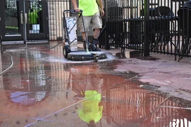 Technician running a surface cleaner across a red stone patio
